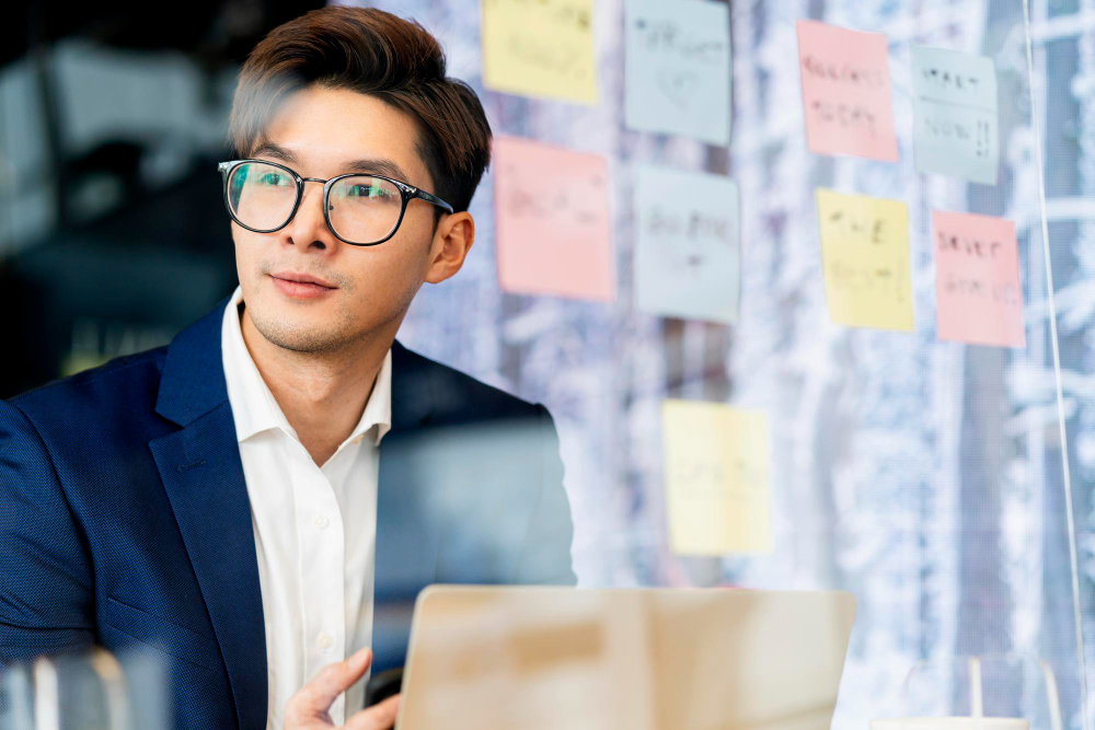 Creative agency smart glasses asian male formal cloth conversation with smartphone freelance working with laptop at coworking area office space with freshness with blur office background